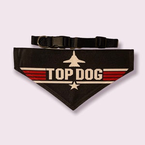 May include: Black dog bandana with a white "Top Dog" logo and a red, white, and blue fighter jet graphic. The bandana is attached to a black adjustable collar.