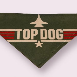 May include: Green dog bandana with a white star, red stripes, and the text "TOP DOG" in white. A silhouette of a fighter jet is above the text.