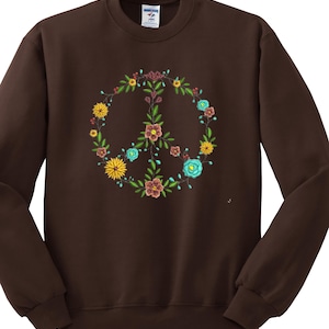 May include: A brown sweatshirt with a peace sign made of flowers in shades of yellow, blue, red, and green.