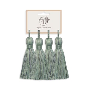 Puede incluir: Conjunto de cuatro borlas de adorno para cojines, a rayas verdes y azules. Las borlas están sujetas a una tarjeta que dice "Laura Ashley 70 años - Borla para cojín Bedford".