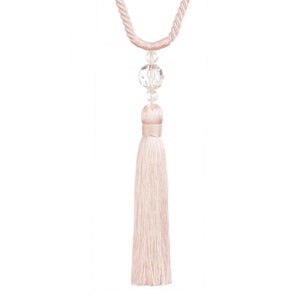 Pode incluir: Um delicado tassel rosa com um detalhe de contas de cristal. O tassel é feito de fios macios e sedosos e pendura em um cordão de corda.