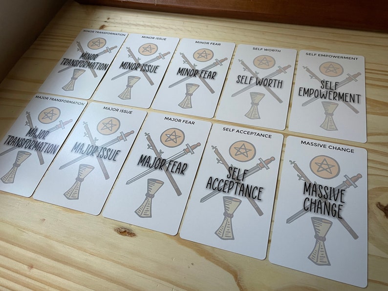 May include: A set of ten tarot cards with various themes, including self-worth, self-empowerment, self-acceptance, and major transformation. Each card features a pentacle, two swords, and a goblet.
