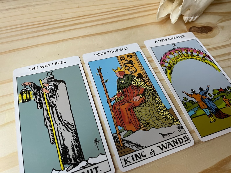 May include: Three tarot cards, "The Way I Feel" with the IX of Swords card, "Your True Self" with the King of Wands card, and "A New Chapter" with the X of Cups card.
