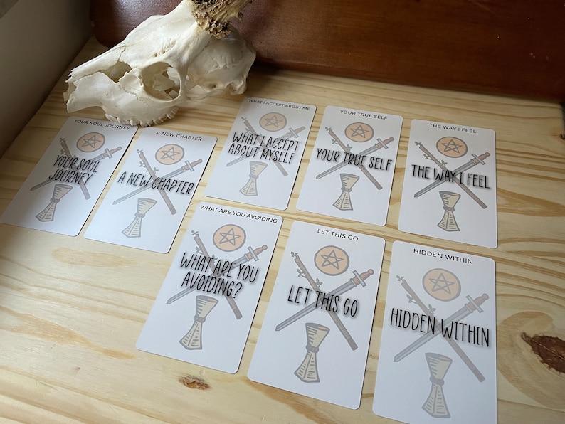 May include: A set of ten tarot cards with white backgrounds and black text. Each card features a pentacle, two swords, and a phrase. The phrases include "Your Soul Journey", "A New Chapter", "What I Accept About Myself", "Your True Self", "The Way I Feel", "What Are You Avoiding", "Let This Go", "Hidden Within", and more.