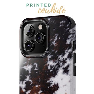 May include: A black phone case with a printed cowhide pattern. The case has a raised camera bump with three lenses.