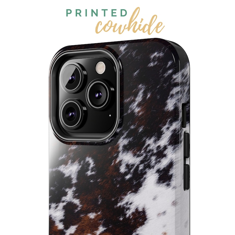 May include: A black phone case with a printed cowhide pattern. The case has a raised camera bump with three lenses.