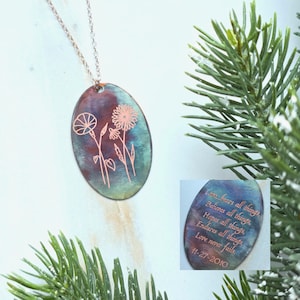 Może przedstawiać: Naszyjnik z owalną zawieszką i łańcuszkiem w kolorze miedzi. Zawieszka ma niebieskie, fioletowe i miedziane tło z wytrawionymi kwiatami. Tekst "Love...bears all things. Believes all things. Hopes all things. Endures all things. Love never fails. 11-27-2010" jest wytrawiony na mniejszej zawieszce.