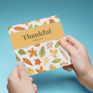 Tarjeta de agradecimiento con temática de otoño para imprimir, hojas otoñales naranjas, amarillas y verdes con una pancarta naranja, agradecimiento por ti, saludos de Acción de Gracias