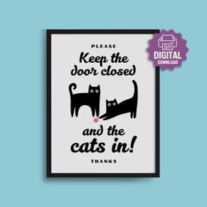 May include: A framed print with a black border and a light grey background. The print features two black cat silhouettes and the text "Please Keep the door closed and the cats in!" with a small pink ball of yarn.