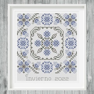 Op de afbeelding: Een kruissteekpatroon met een blauw en grijs bloemenmotief met de tekst "Invierno 2022".