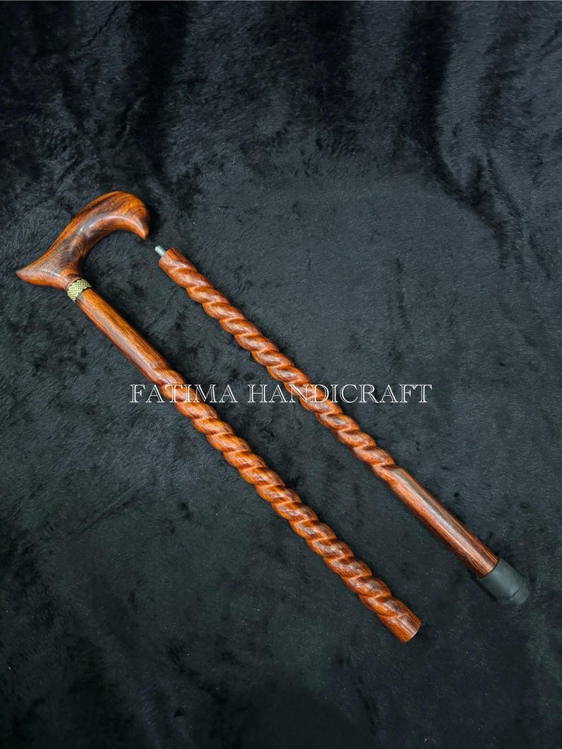 Op de afbeelding: Twee houten wandelstokken met een donkerbruine afwerking en een gedraaid ontwerp. E&eacute;n stok is geassembleerd met een gebogen handvat en een gouden accent. De andere stok is gedemonteerd. De tekst "FATIMA HANDICRAFT" staat op de afbeelding.