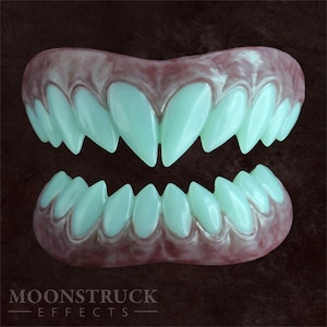 Könnte beinhalten: Ein Satz realistischer, grün leuchtender Vampirzähne. Die Zähne sind aus einem weichen, flexiblen Material gefertigt und so konzipiert, dass sie über die eigenen Zähne passen. Sie sind perfekt für Halloween-Kostüme oder Cosplay.