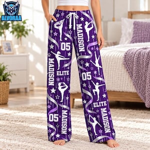 May include: Purple lounge pants with a white drawstring waist featuring a repeating pattern of white gymnast silhouettes, stars, ribbons, and the text "MADISON", "ELITE", and "05" printed throughout the fabric in a vertical orientation.