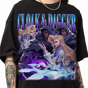 May include: Black t-shirt with a graphic print of four characters from the Cloak & Dagger comic book series. The characters are wearing colorful costumes and are surrounded by purple and blue lightning bolts.
