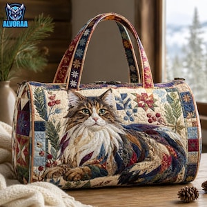 May include: A quilted barrel-shaped handbag featuring a detailed image of a long-haired brown and white cat. The bag is decorated with a patchwork pattern of pine branches, red berries, and geometric star motifs in shades of blue, red, and cream.