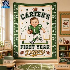 May include: A rectangular wall tapestry featuring a football theme with a central illustration of a baby in a green jersey holding a football. The text reads CARTER'S FIRST YEAR DOWN. The border resembles a football field with yard line markers.
