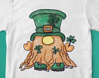 Peut inclure: T-shirt blanc avec une illustration de gnome de la Saint-Patrick. Le gnome porte un chapeau vert avec un trèfle, un visage jaune et une barbe orange. Le motif comprend des trèfles verts et des chaussures vertes.