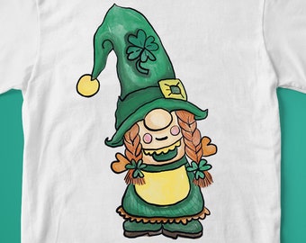 Peut inclure: T-shirt blanc avec une illustration de dessin animé d'un gnome lutin vert portant un chapeau vert avec un motif de trèfle. Le gnome a les cheveux roux, un tablier jaune et un sourire amical.
