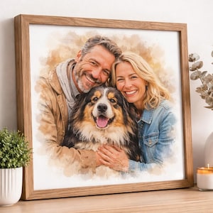 May include: A framed watercolour portrait of a smiling couple and their dog. The artwork depicts a man and woman hugging a tri-colour dog with a happy expression. The frame is light brown wood, and the background has soft, warm tones.