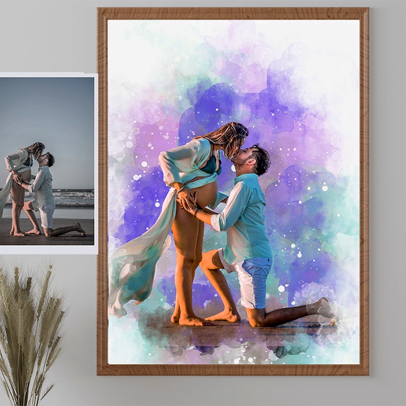 May include: A framed watercolor print depicts a couple kissing, with the man kneeling and the woman standing, embracing her pregnant belly. The background features a watercolor wash of purple, blue, and green hues. A smaller photo is in the upper left corner.