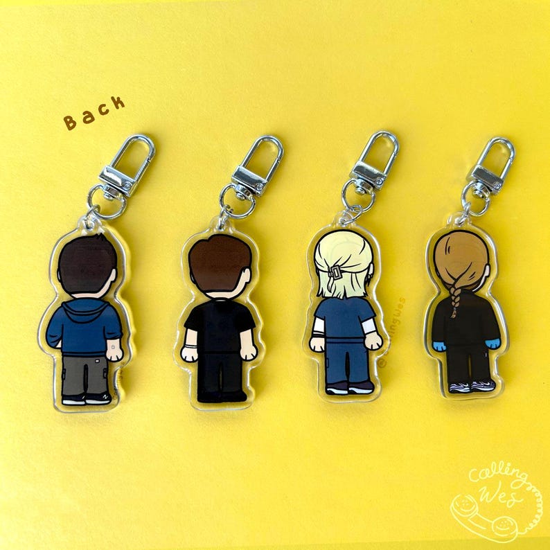 May include: Four acrylic keychains with silver-colored hardware. Each keychain features a cartoon figure with different hairstyles and outfits. The figures are shown from the back. The background is yellow with the word "Back" in the upper left corner.
