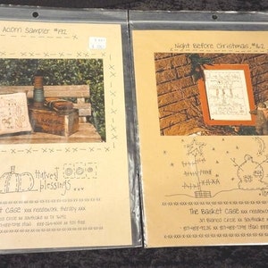 May include: Two cross-stitch patterns, one titled "Acorn Sampler #192" and the other "Night Before Christmas #162". Both patterns feature a small pillow with a cross-stitch design and the text "Harvest Blessings".
