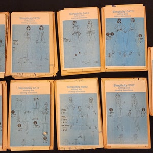 May include: A collection of ten vintage Simplicity sewing patterns, featuring various designs for dresses, skirts, and jackets. The patterns are printed on blue paper with black illustrations and text.