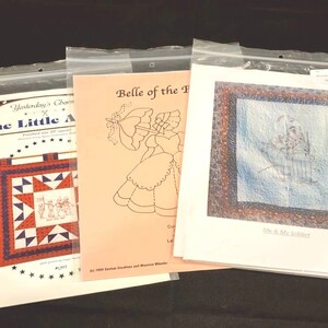 May include: Three quilting patterns in plastic bags. The patterns are titled "The Little Angel", "Belle of the Ball", and "Me & My Soldier".