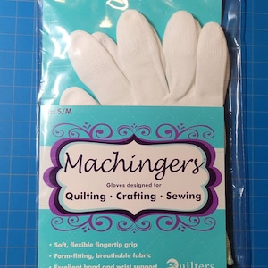 May include: White cotton gloves with a flexible fingertip grip, designed for quilting, crafting, and sewing. The packaging features the brand name "Machingers" and the tagline "Gloves designed for Quilting. Crafting. Sewing."