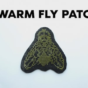 May include: A black and green embroidered patch depicting a fly. The patch has the text "SWARM FLY PATCH" above it.