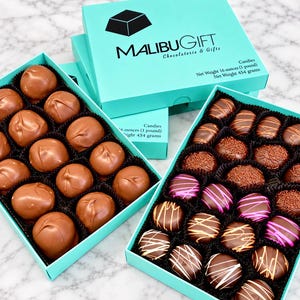 Op de afbeelding: Twee turquoise dozen met MalibuGift Chocolaterie & Gifts chocolaatjes. De ene doos bevat gladde, ronde melkchocoladetruffels. De andere doos bevat diverse chocolaatjes met hagelslag en gekleurde glazuurstrepen. Nettogewicht 454 gram.