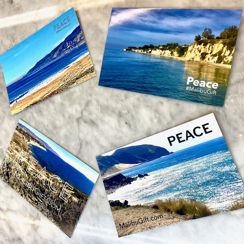 Op de afbeelding: Vier rechthoekige ansichtkaarten met kustlandschappen met blauw zeewater, zandstranden en kliffen. Elke kaart toont het woord PEACE en de tekst MalibuGift.com of #MalibuGift in witte of zwarte letters over de landschappelijke beelden.