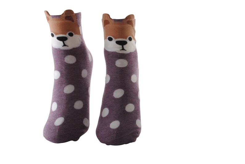 May include: A pair of purple socks with white polka dots and a brown dog face on the top of each sock.