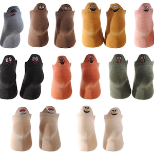 Op de afbeelding: Een set van 18 kleurrijke sokken met geborduurde cartoongezichten. De sokken zijn in verschillende kleuren, waaronder blauw, bruin, oranje, groen, roze en beige. Elke sok heeft een ander cartoongezicht met een unieke uitdrukking.