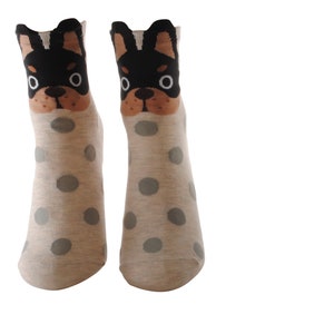 May include: A pair of grey ankle socks with white polka dots and a black and brown dog face design on the top of each sock.