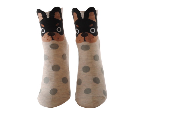 May include: A pair of grey ankle socks with white polka dots and a black and brown dog face design on the top of each sock.