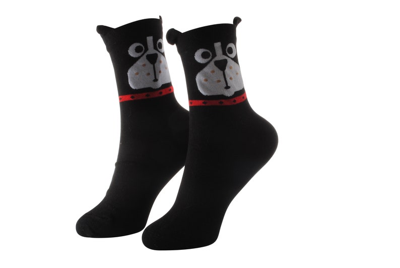 May include: A pair of black socks with a white and gray dog face design. The dog has a red collar.