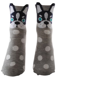 May include: A pair of gray socks with white polka dots and a black and white dog face design on the top of each sock.