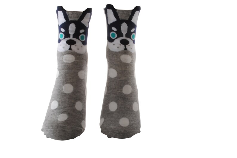 May include: A pair of gray socks with white polka dots and a black and white dog face design on the top of each sock.