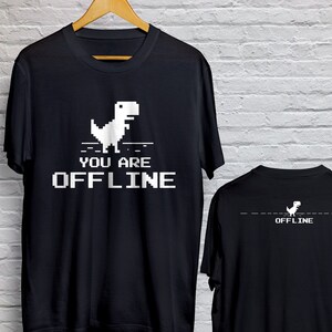 May include: Black t-shirt with a white pixelated dinosaur graphic and the text "YOU ARE OFFLINE" on the front. The back of the shirt features the dinosaur graphic and the word "OFFLINE".