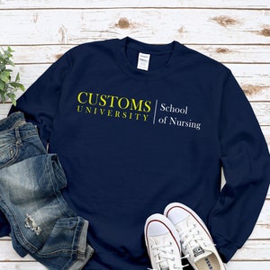 Peut inclure: Un sweat-shirt bleu marine avec le texte "CUSTOMS UNIVERSITY | School of Nursing" en jaune.