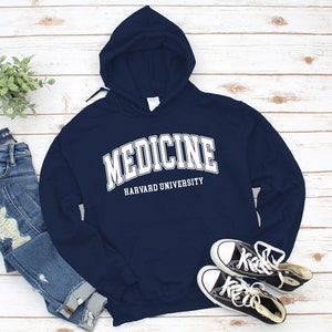 Könnte beinhalten: Dunkelblauer Kapuzenpullover mit weißem Text, der "MEDICINE HARVARD UNIVERSITY" lautet.