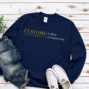 Peut inclure: Sweat-shirt à manches longues bleu marine avec le texte "CUSTOMS UNIVERSITY College of Engineering" en jaune.