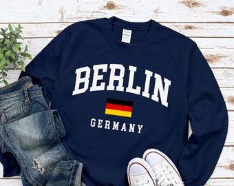 May include: Navy blue sweatshirt with white text that reads "BERLIN GERMANY" and a small German flag.