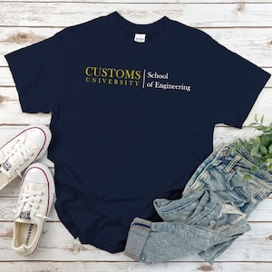 Puede incluir: Una camiseta azul marino con el texto "CUSTOMS UNIVERSITY | School of Engineering" en letras amarillas.