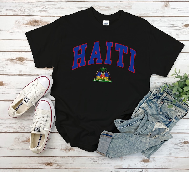 Op de afbeelding: Zwart T-shirt met een blauwe en rode "HAITI" afbeelding met de Ha&iuml;tiaanse vlag eronder.