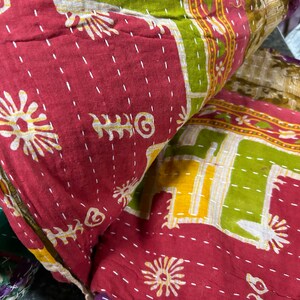May include: A colorful kantha quilt with a red, green, and yellow patchwork design. The quilt is made of cotton and has a hand-stitched pattern.