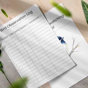 May include: Two white sheets of paper with the text "Bird Observation Log" and "Bird watching journal". One sheet has a grid for recording bird sightings. The other has a watercolor illustration of a blue and white bird on a branch.