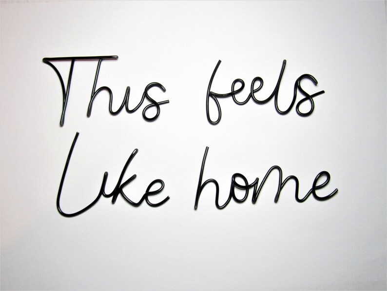 May include: Black metal wire wall decor with the words "This feels like home" in a cursive font.