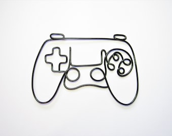 Könnte beinhalten: Eine schwarze Drahtskulptur eines Videospiel-Controllers. Der Controller hat einen Plus-Knopf, zwei runde Knöpfe und einen kreisförmigen Joystick.